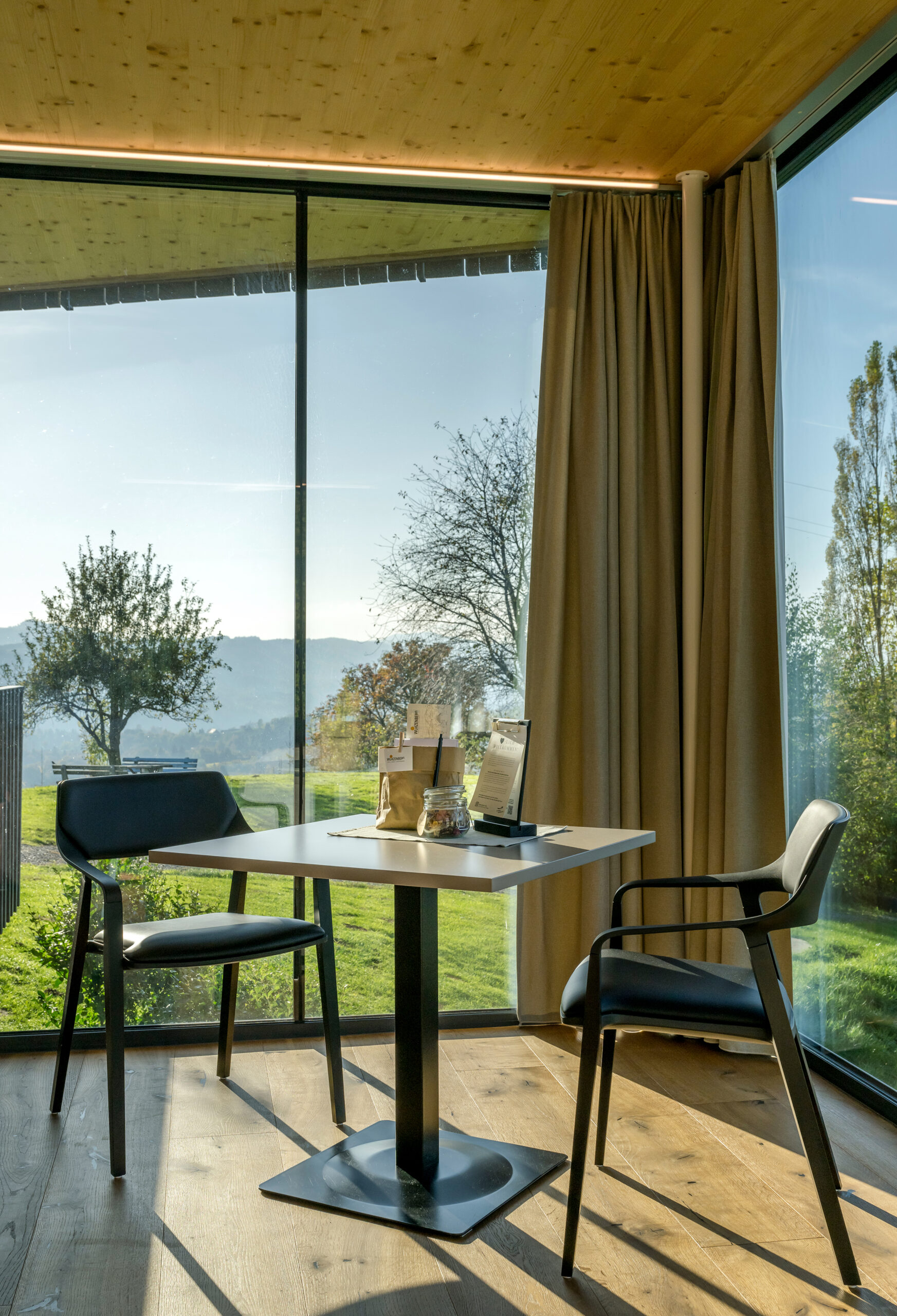 Thymianlodge Innenraum — Raumhohe Glasfront öffnet den Blick in die Landschaft der Südsteiermark.