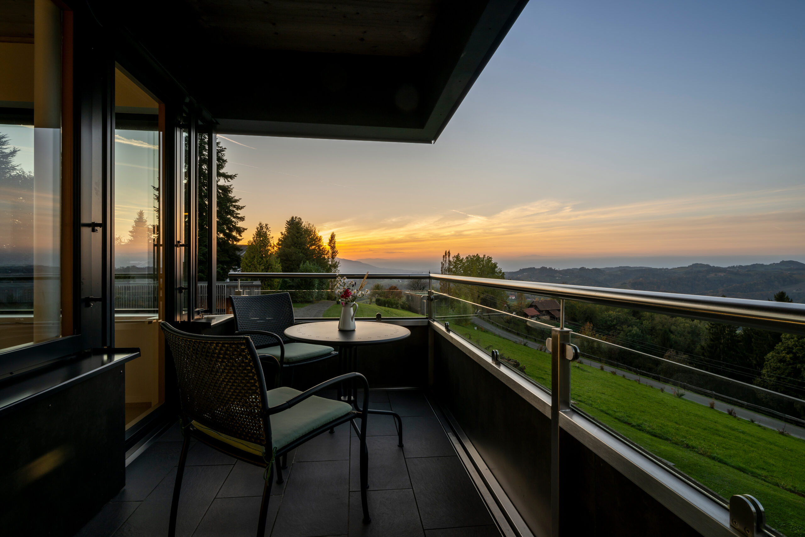 Naturparkzimmer am Wurzenberg — Balkon mit Panoramablick über die Südsteiermark bei Sonnenuntergang.